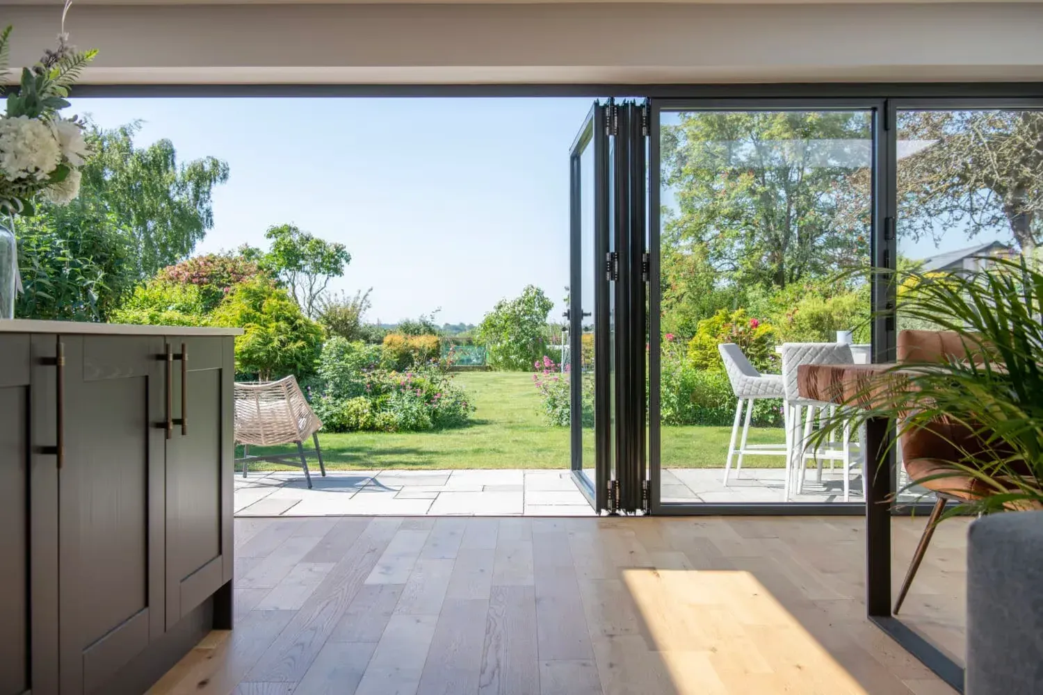 Pintu lipat aluminium kaca atau bifold door terbuka menghadap area taman belakang